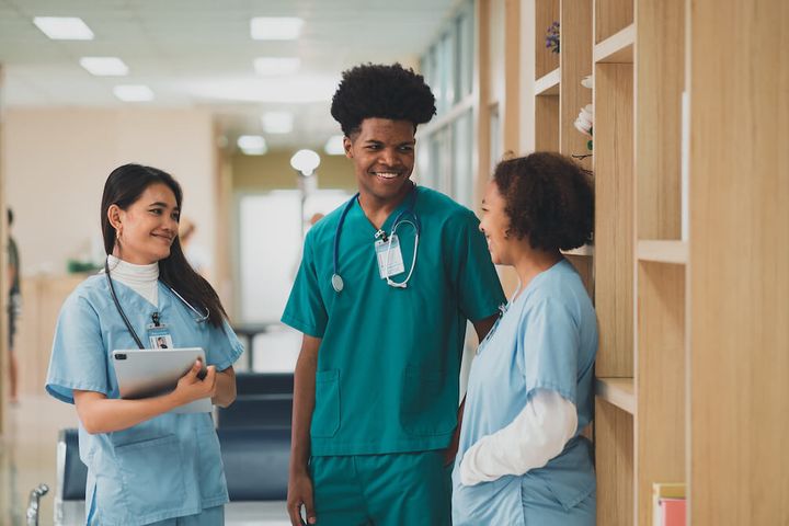 Two female and one male nurse talking together and smiling.