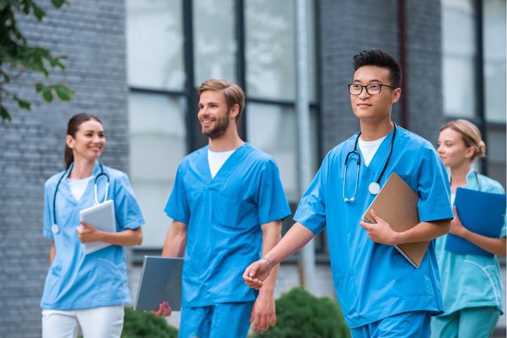 A group of nursing students walk together and discuss colleges with good nursing programs.
