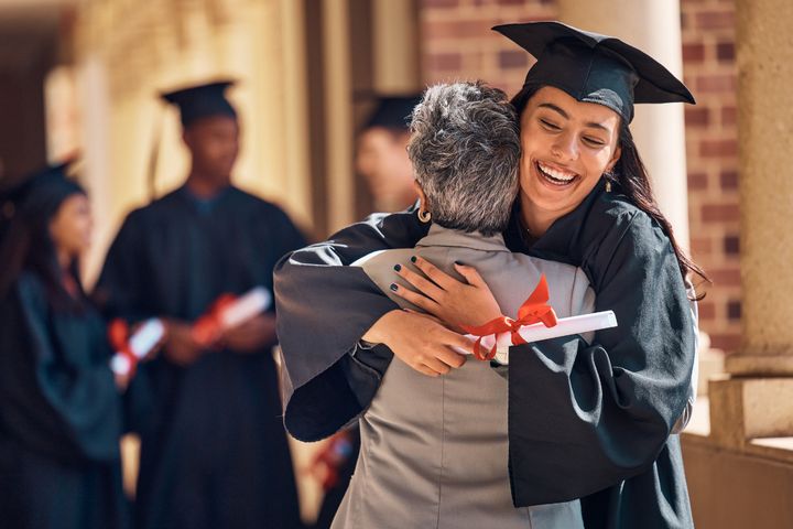 A parent hugs their child after giving them some gifts for a nurse graduate.