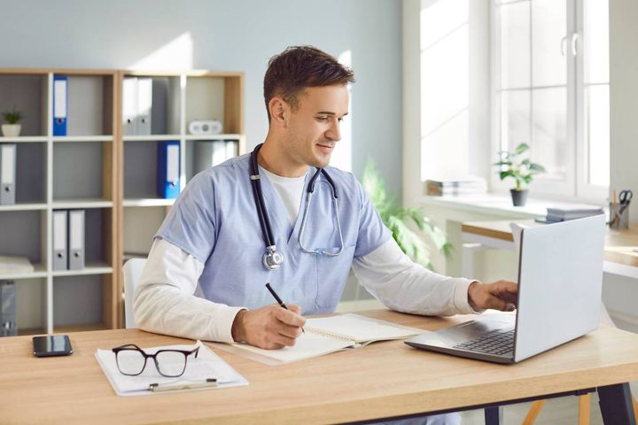 A nurse writes nursing self-evaluation examples on his computer.