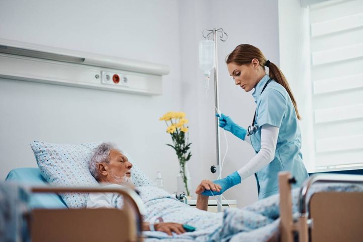 An acute care nurse practitioner checks a patient's IV line.