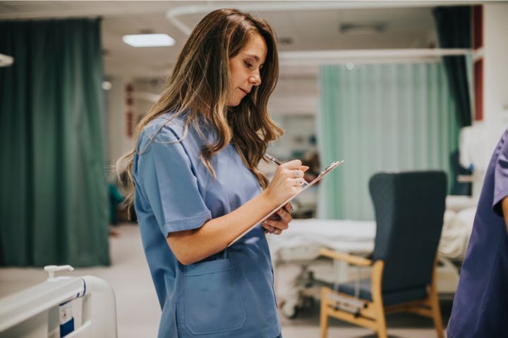 A nurse refers to an acute pain nursing care plan while working with a patient.