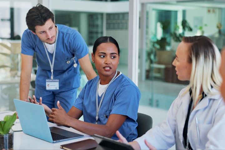 A nurse fills out an assignment despite objection (ADO) form while discussing it with her colleagues.