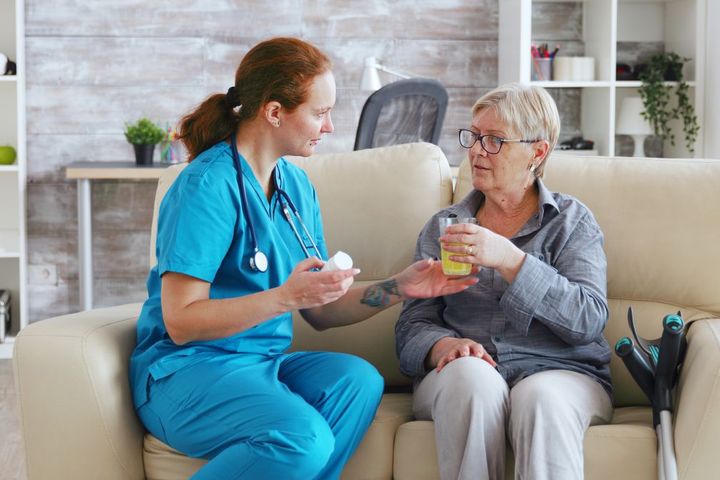 A nurse dispenses pills to a geriatric patient.