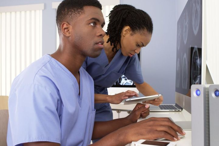 Two nurses look at data and analyze x-ray images.
