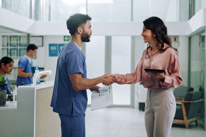 A nurse candidate shakes hands with the supervisor who will interview him.