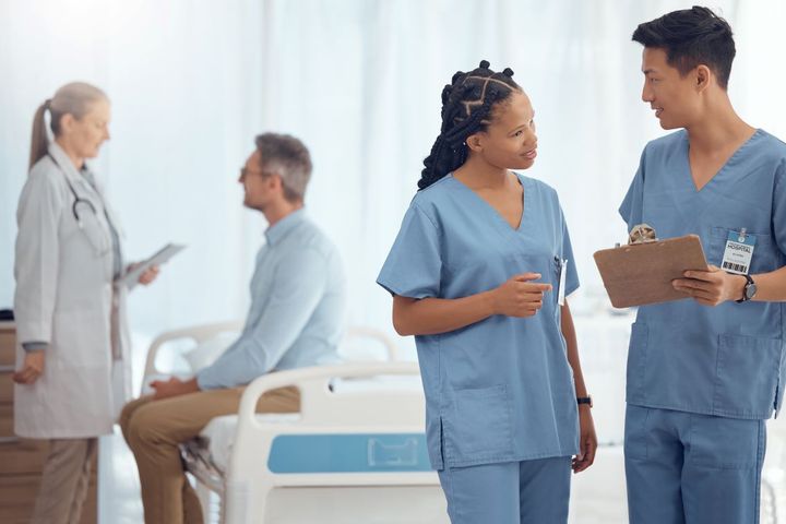A charge nurse meets with one of his coworkers.