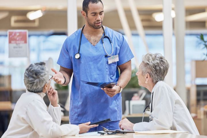 A charge nurse meets with two physicians.