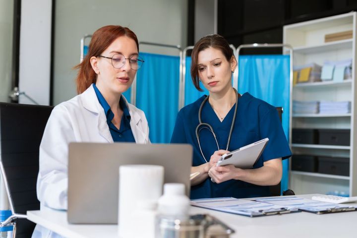 A physician and nurse work out their clinical documentation.