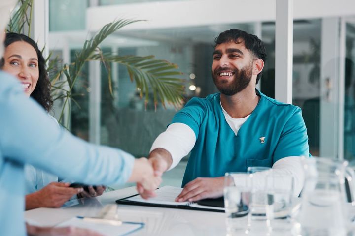 A newly hired nurse shakes the hand of his new supervisor.