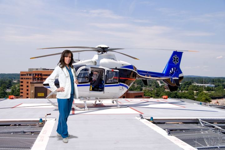 A flight nurse poses in front of her medical response helicopter.