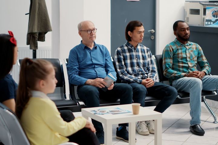 A diverse group of patients in the waiting room of a medical facility.