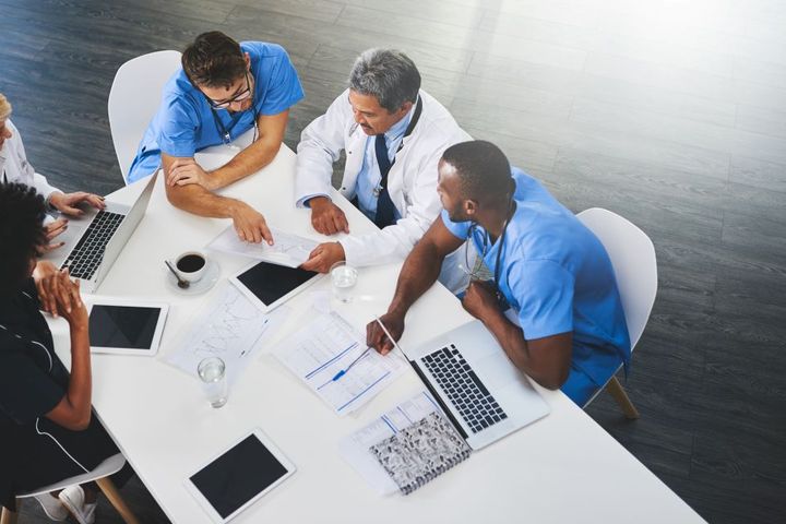 Hospital staff gather at a table and try to fill open positions, with the help of a healthcare ats.