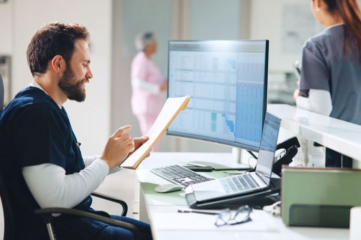 A nurse follows best practices for healthcare cybersecurity as he reviews sensitive documents.