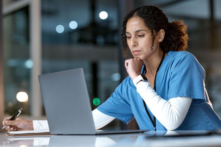A nurse at her computer, figuring out how to create a newsletter for her facility.