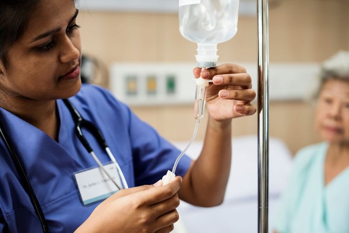 An infusion nurse prepares an IV drip for a patient.