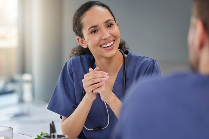 A nurse leader sits down with a colleague to discuss a patient.