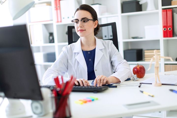 Manager on computer writing a recommendation letter for an LPN