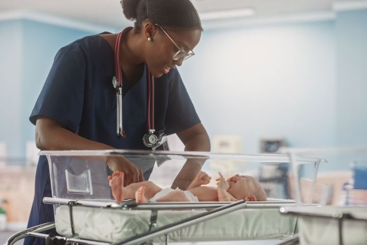 A neonatal nurse checks on a newborn baby.