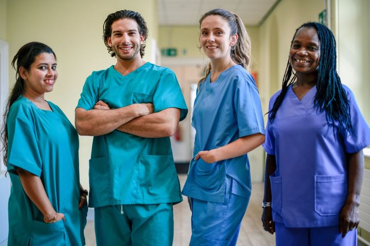 A team of four nurses stands and smiles for the camera.