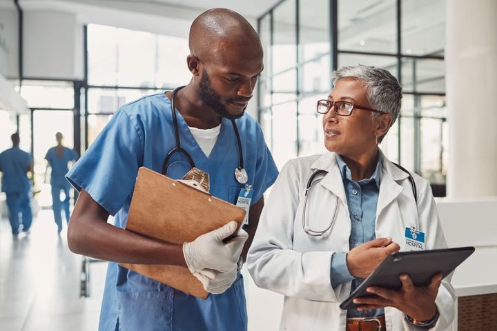 A nurse checking in with his nurse manager in the hallway of a hospital.