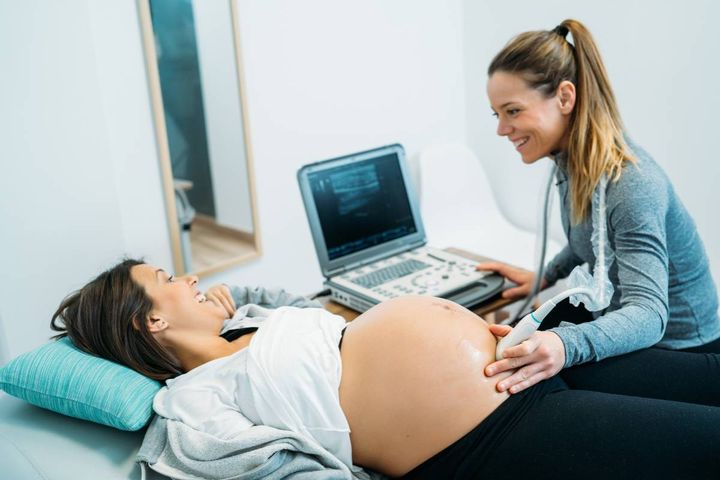 A CNM performs an ultrasound while discussing nurse midwife salary expectations.