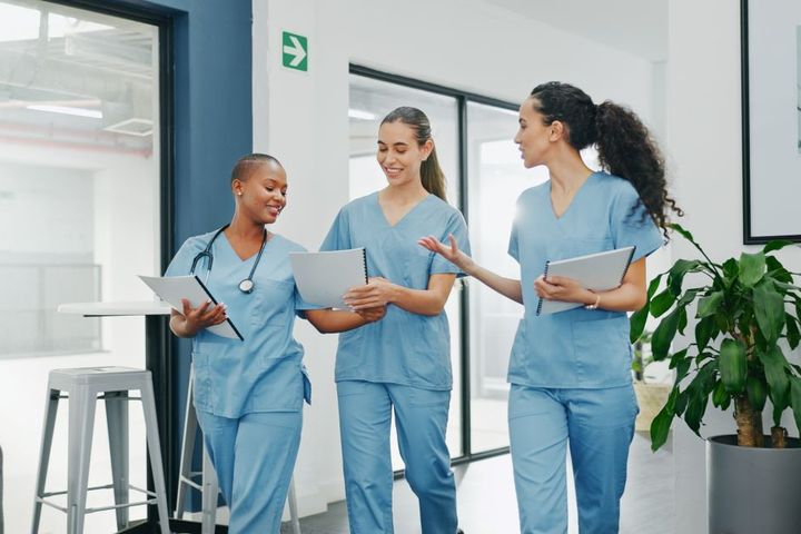 Three nurses walk down a facility hall together.