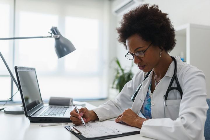 A nurse practitioner looks at her patient chart as she sits at her desk.