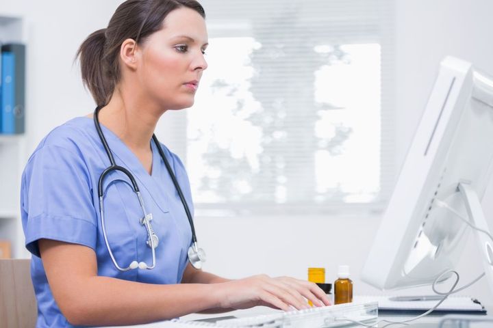 A nurse sits at the computer and types a nurse recommendation letter for a former colleague.
