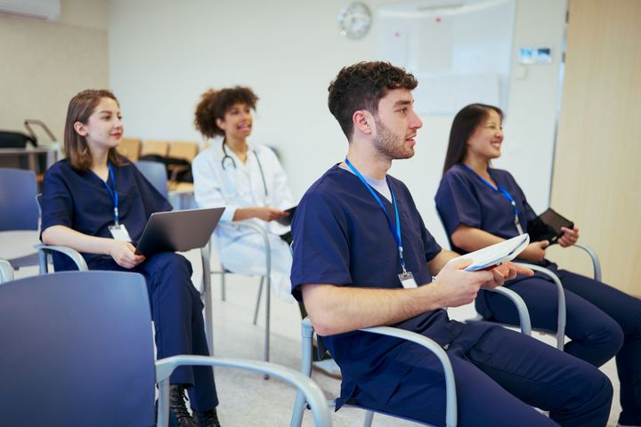A group of nurses listen as a nursing professional development specialist provides training.