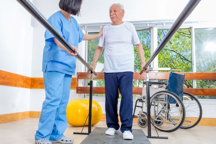 A long term care nurse helps a resident with his daily physical therapy.