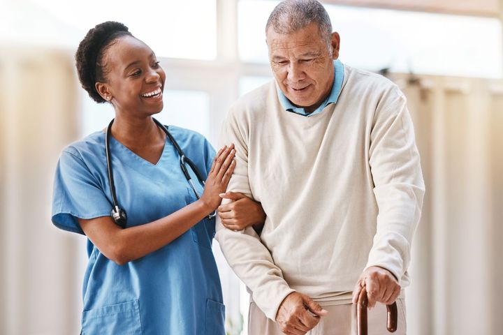 A nurse assists a nursing home resident with walking.