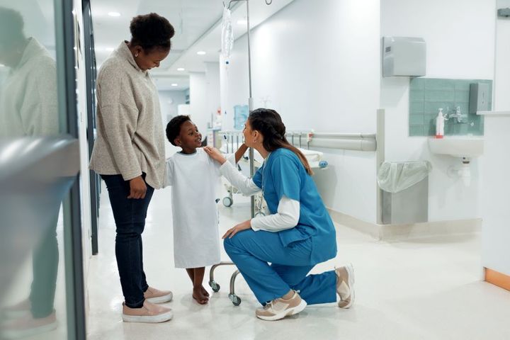 An OR nurse meets with a child patient prior to an operation.