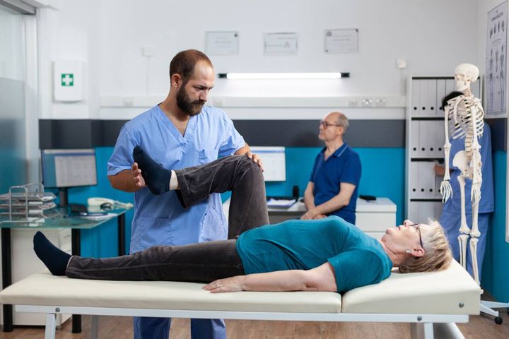 A nurse with orthopedic nurse certification (ONC) assesses a patient's knee.