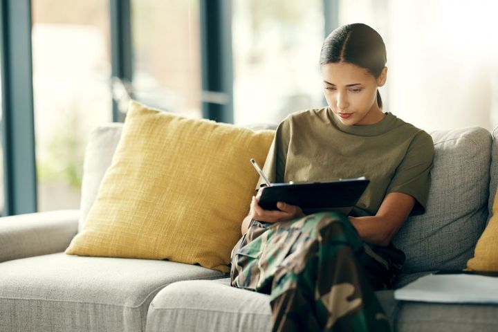 A woman, sitting on her couch at home, fills out a patient experience survey after her hospital visit.