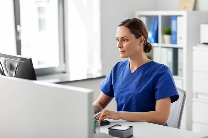 Nurse in blue scrubs updates their pediatric nurse resume.