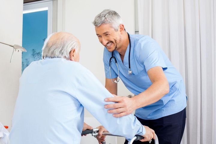 A nurse helps a nursing home resident who's at a high risk for falls use his walker.