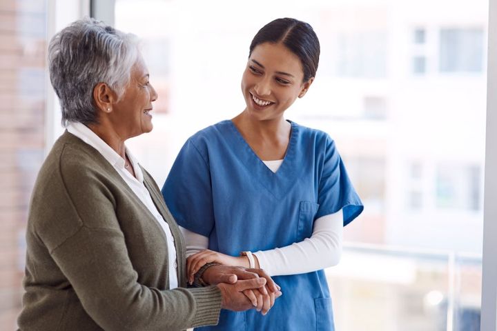 Nurse smiling and holding a patient's arm