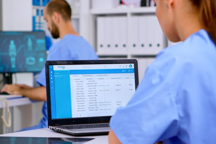A nurse looks up source-oriented medical records on a laptop computer.