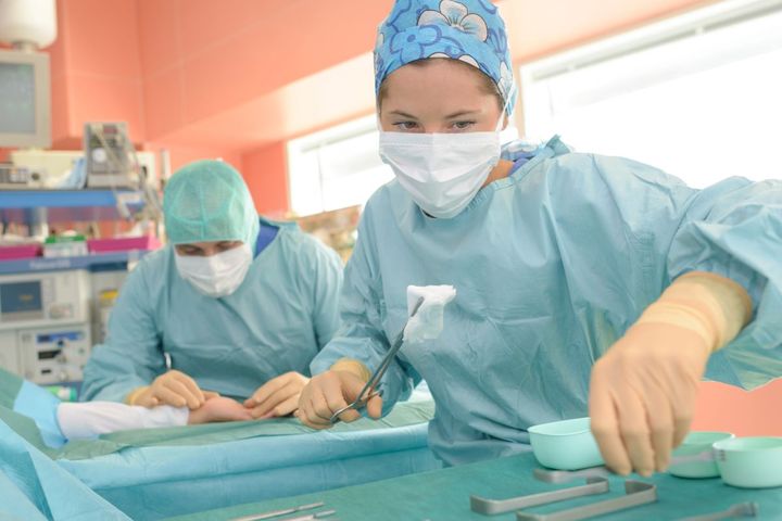 A surgical tech assists with a surgical procedure.