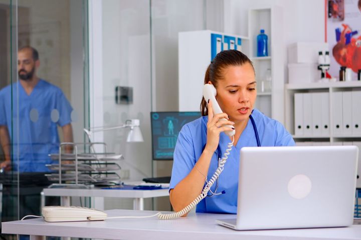 A telehealth nurse talks to a patient while looking at information on a laptop computer.