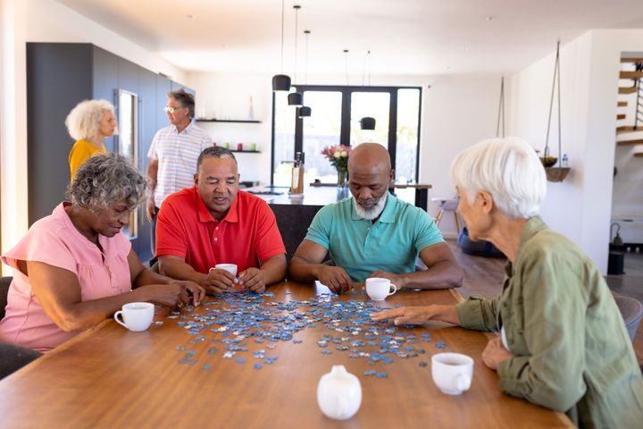 Residents at an assisted living facility, or "ALF," enjoying time together and working on a puzzle.
