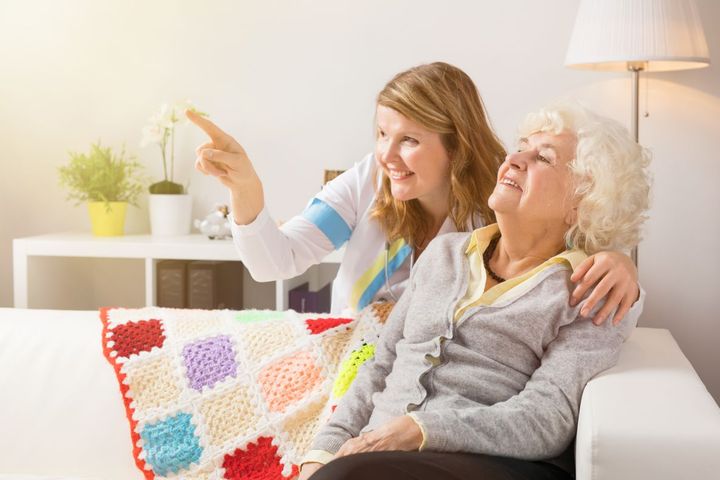 A woman points to a camera in the room she's showing to her mother, who is a nursing home resident.