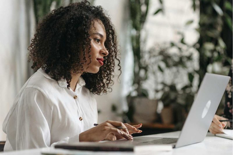 Young woman in white shirt on laptop.
