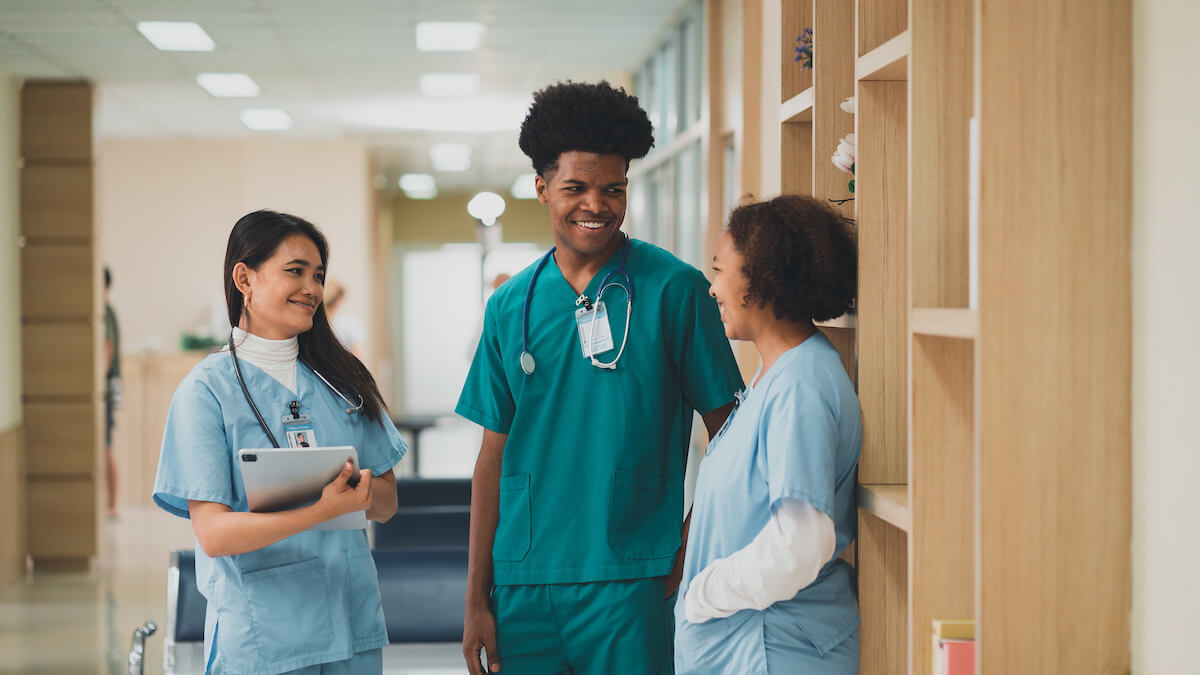 Two female and one male nurse talking together and smiling.