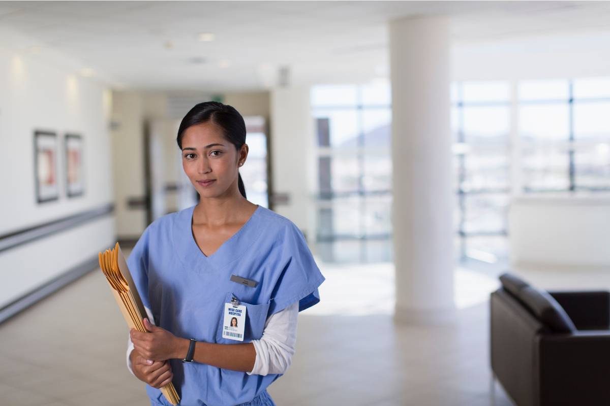 A nurse with PMHCNS-BC certification poses for a photo in a hospital hallway.