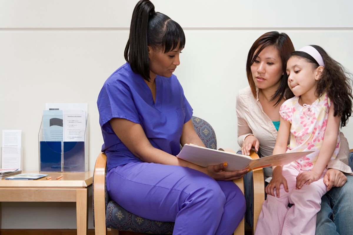 An ambulatory care nurse reads a book to one of her young patients.