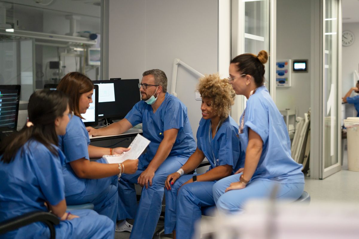 A team of nurses looks at a readout near a computer.
