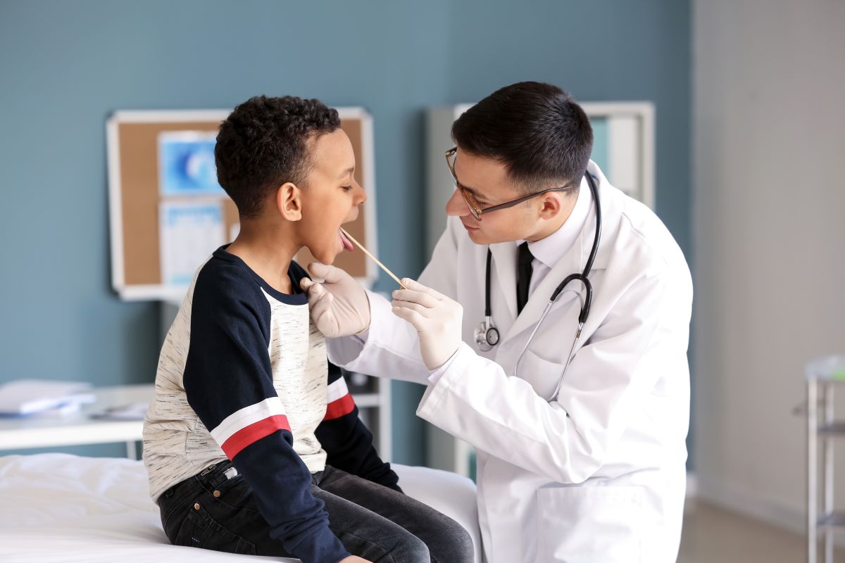 A physician checks a patient's throat.