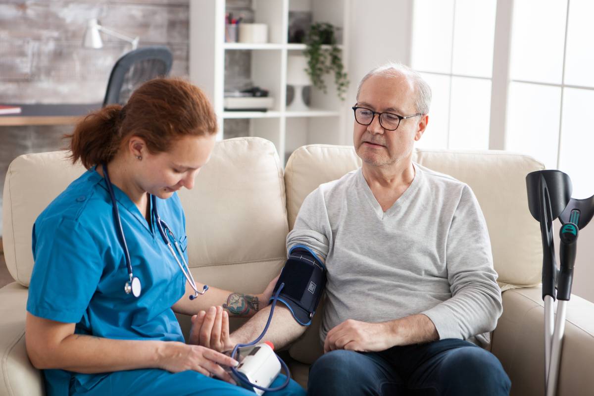 A nurse with CV-BC certification takes a patient's blood pressure.
